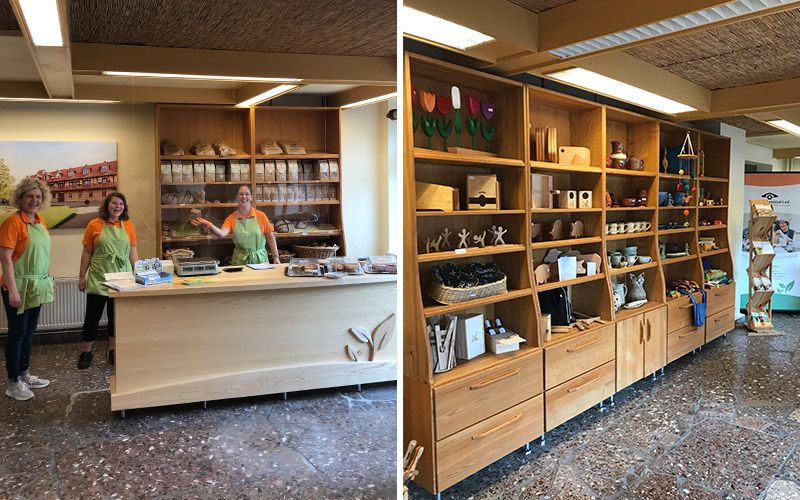 Bild zeigt fröhliche Mitarbeitende am Verkaufstresen und verschiedene Artikel aus Holz und Keramik in Regalen im Gutshofladen.