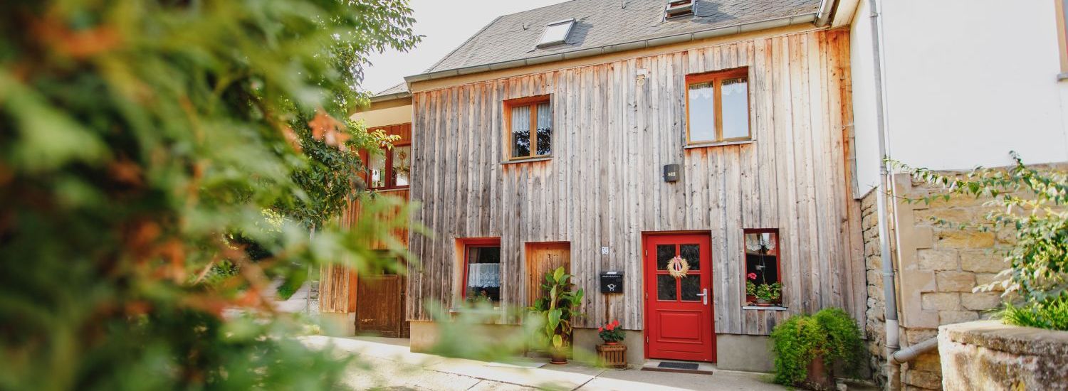 Ein Wohnhaus mit Holzverkleidung und einer roten Eingangstür.