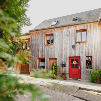 Ein Wohnhaus mit Holzverkleidung und einer roten Eingangstür.