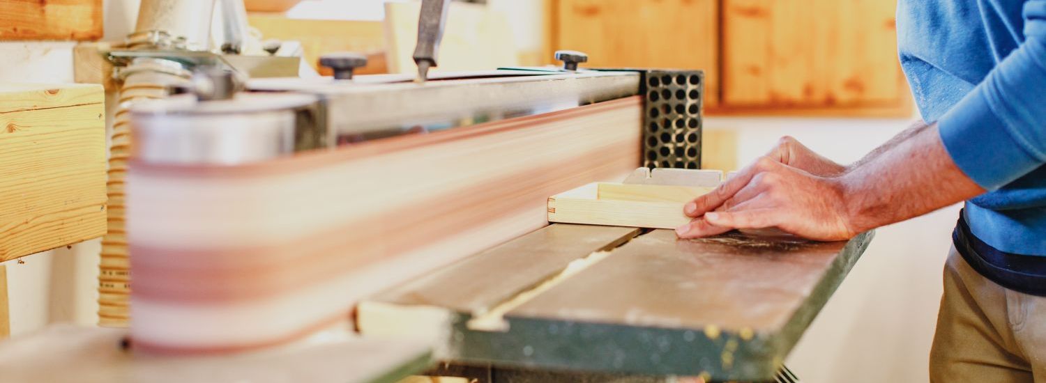 Ein Holzkästchen wird an einer Schleifmaschine bearbeitet.